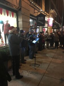 Carolers in Downtown Mystic A group of musicians play holiday music in front of stores decorated for Christmas.